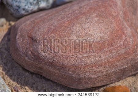 Beautiful Smooth Sea Stones In The Sands Of The Beach. Closeup Photo Of Stone Textures And Shapes.