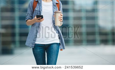 Woman Walking With Coffee Themo Cup In Hand On City Street