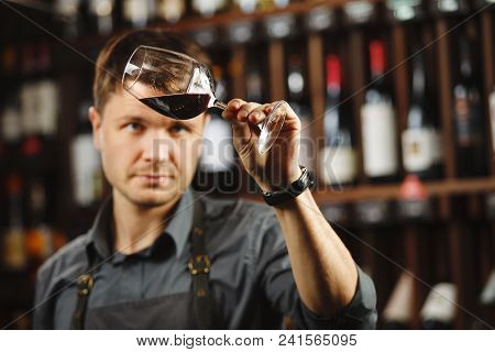 Bokal Of Red Wine On Background Of Male Sommelier Appreciating Color, Quality, Flavor And Sediments 