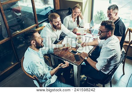 Young Cheerful People Smile And Gesture While Relaxing In Pub. Team Job. Photo Young And Mature Busi