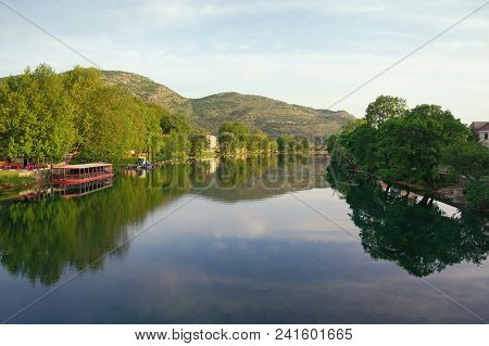 Beautiful Landscape With Calm River, Green Trees On Banks And Their Reflection In The Water.  Bosnia