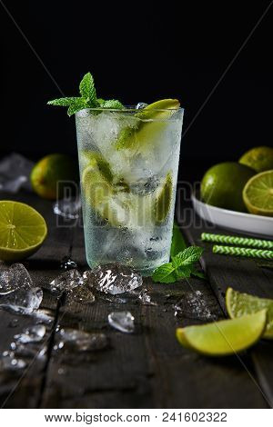 Mojito Cocktail With Lime And Mint In Highball Glass With Ice On A Dark Wood Background With Copy Sp