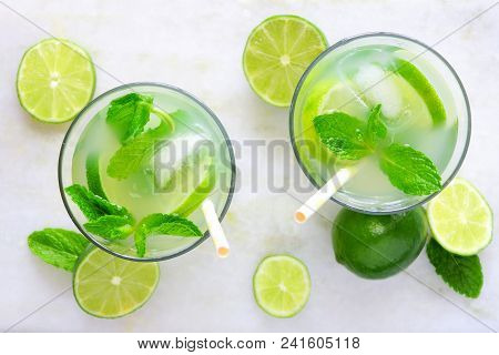 Two Glasses Of Summer Limeade With Mint. Top View On A White Marble Background.
