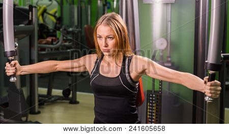 Pretty Caucasian Smiling Woman Is Working Out On Butterfly Machine In Gym