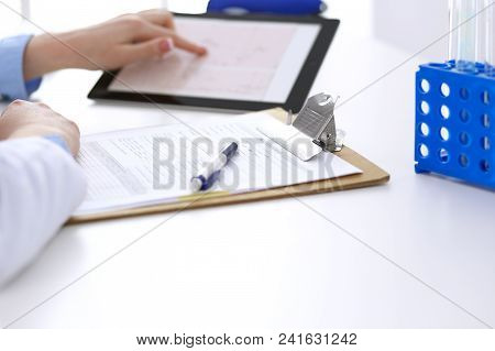 Woman Doctor Using Tablet Computer While Sitting At The Desk In Hospital Closeup. Cardiologist Check