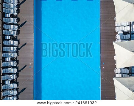 A top view swimming pool with beds and umbrellas in garden