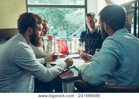 Young Cheerful People Smile And Gesture While Relaxing In Pub. Team Job. Photo Young And Mature Busi