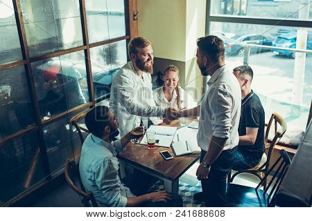 Young Cheerful People Smile And Gesture While Relaxing In Pub. Team Job. Photo Young And Mature Busi
