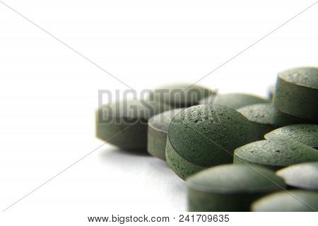 Close Up Of Many Organic Spirulina Tablets With Low Depth Of Field Over White Background.