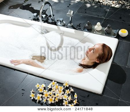 ผู้หญิงวางใน soapsuds ในการอาบน้ำที่เต็ม