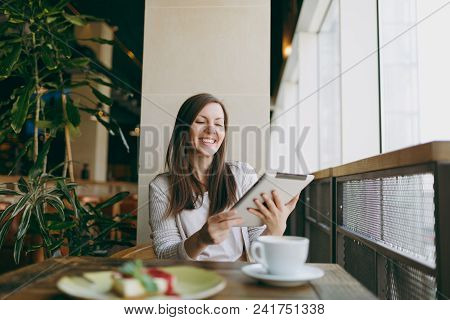Woman Sitting Alone Near Big Window In Coffee Shop At Table With Cup Of Cappuccino, Cake, Relaxing I