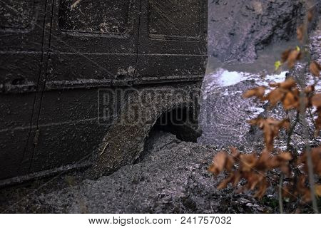 Wheel In Deep Puddle Of Mud. Dangerous Expedition Concept. Offroad Tire Covered With Mud On Nature B