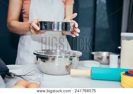 A Woman Sifting Flour Into A Stainless Bowl. Girl Is Sifting Flour To Making The Bakery In Her Kitch