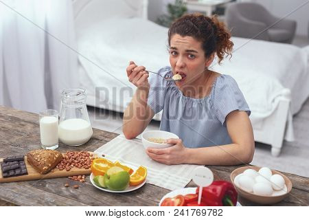 Healthy Ratio. Young Lady Looking Bored Sitting At The Table Taking Another Spoonfull Of Her Morning