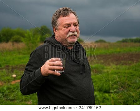 ussia. Drunk elderly mustachioed man with a glass of pink wine portrait in nature