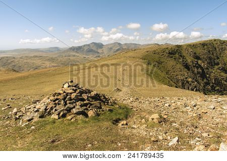 Cairn Next To A Stoney Footpath In The Lake District, Uk. The Path, Marked With Multiple Cairns, Lea