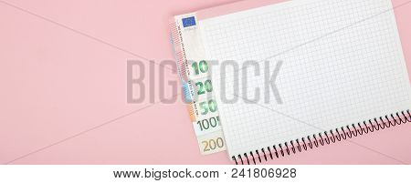 Notebook And Money On The Table. Notepad And Euro Banknotes On A Pink Background With Copy Space. Bu