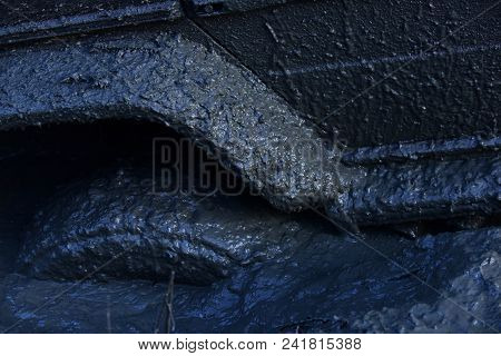 Fragment Of Car Stuck In Dirt, Close Up. Wheel In Deep Puddle Of Mud Overcomes Obstacles. 4x4 Racing