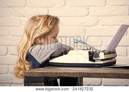 Writer Kid Or Small Boy Or Businessman Child With Blonde Hair Sitting At Table And Typing Typewriter