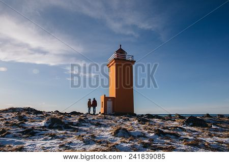 Young Couple Holding Hands And Standing Near Lighthouse In Iceland, Stafnesviti, Reykjanes