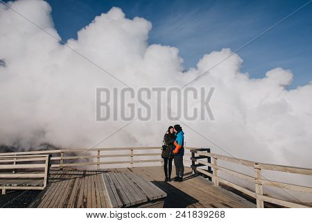 Young Couple Standing Together And Steam From Geothermal Hot Springs Behind, Reykjanes, Gunnuhver Ho