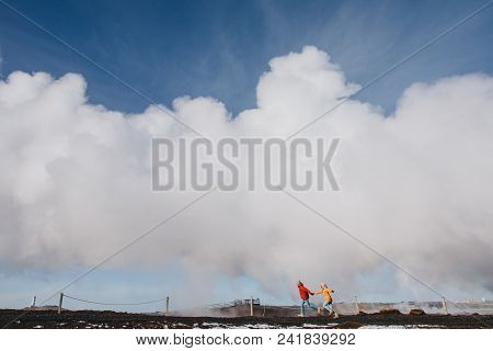 Young Couple Holding Hands And Running Near Geothermal Hot Springs In Iceland, Reykjanes, Gunnuhver 