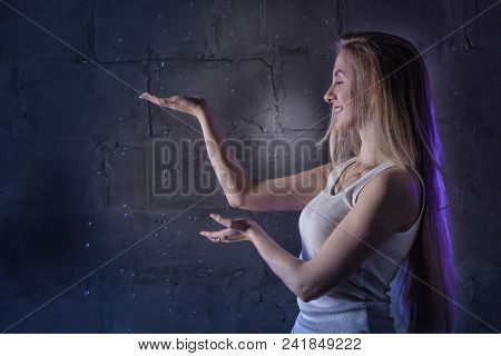 Portrain Of The Girl In The White Shirt With Water Drop In A Dark Room Illuminated By Light During A