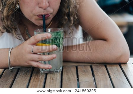 Midsection Of Woman Drinking Lemonade Glass On Table.
