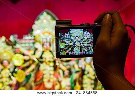 Camera In Hand Taking Photo Of Durga Idol In Background Shallow Depth Of Field