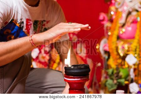 A Hand Taking Heat Of The Flame As Blessing From A Lit Clay Lamp On Top Of A Clay Stand Or Worship I