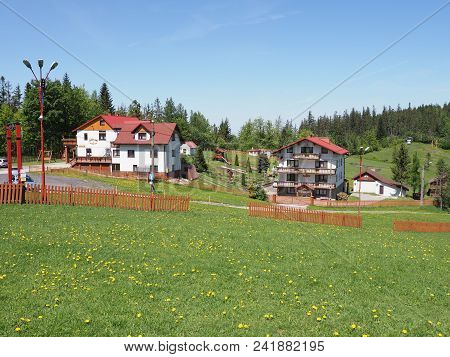 Salmopol, Poland On May 2018: Houses In Countryside Landscapes Of Grassy Field And Forest At Beskid 
