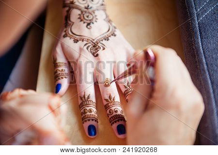 Drawing Mehndi On The Hand Of A Girl