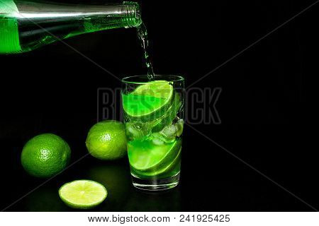 Summer Refreshing And Beverages Concept. Glass Of Cold Drink With Ice And Fresh Ripe Slice Green Lim