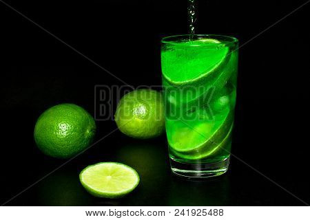 Summer Refreshing And Beverages Concept. Glass Of Cold Drink With Ice And Fresh Ripe Slice Green Lim