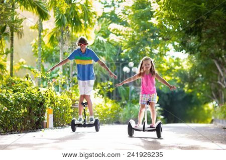Child On Hover Board. Kids Riding Scooter In Summer Park. Balance Board For Children. Electric Self 