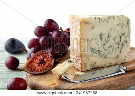 Stilton On A Cheese Board With Red Grapes, Fig And Cheese Knife