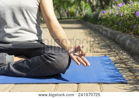 Closeup Of Young Man Meditating In Lotus Pose And Practicing Hand Mudra Outdoors On Mat With Pavemen