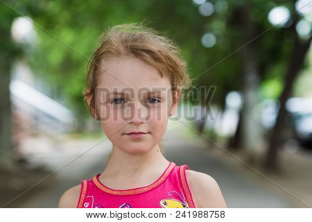 Portrait Of Child Girl With A Sly Look In Summer