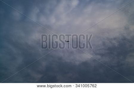 A Jet Flies High Above Beneath A Cloudy Sky