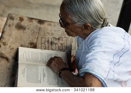 November 30, Maharashtra India, - An Elderly Lady In White Dress Reading Books In The Evening At Gan