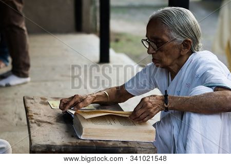 November 30, Maharashtra India, - An Elderly Lady In White Dress Reading Books In The Evening At Gan