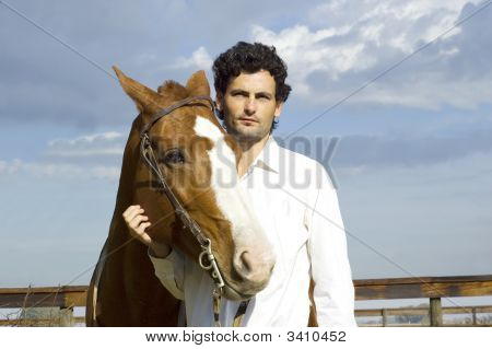 Giovane uomo in piedi con il suo cavallo