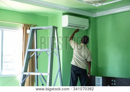 Workers Repairs And Cleans The Air Conditioner In The Room. Steel Ladder Used By The Worker To Climb