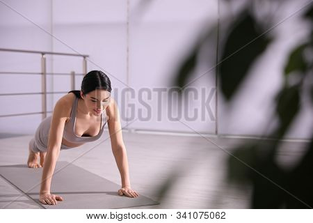Young Woman Practicing Plank Asana In Yoga Studio. Phalankasana Pose