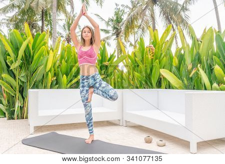 Teanage girl stretching surronded by tropical plants