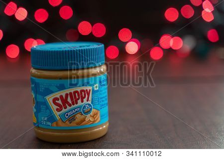 Minneapolis, Minnesota - December 23, 2019: Skippy Brand Peanut Butter Sitting On A Table, Red Bokeh