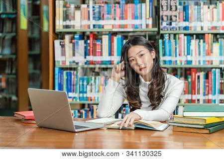 Asian Young Student In Casual Suit Thinking When Doing Homework And Using Technology Laptop In Libra