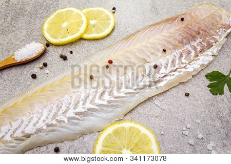 Fresh Raw Hake Fillet On A Stone Background. With Lemon, Parsley, Salt In Wooden Spoon And Peppers M