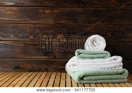 Folded Towels On Bamboo Table Against Wooden Background, Space For Text