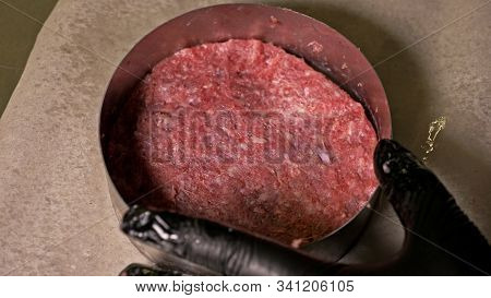 Cook Makes Meat Medallions For Burgers. Chef In Black Food Gloves Makes Cutlet. Cutlets Are Leveled 